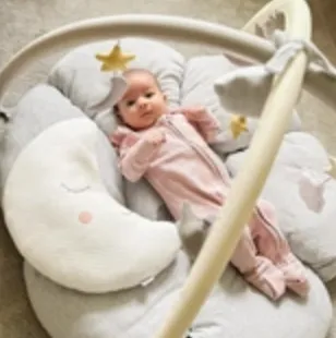 Baby lying on blanket underneath mobile