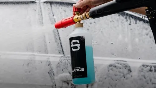 Close up of a car door being sprayed with cleaning foam