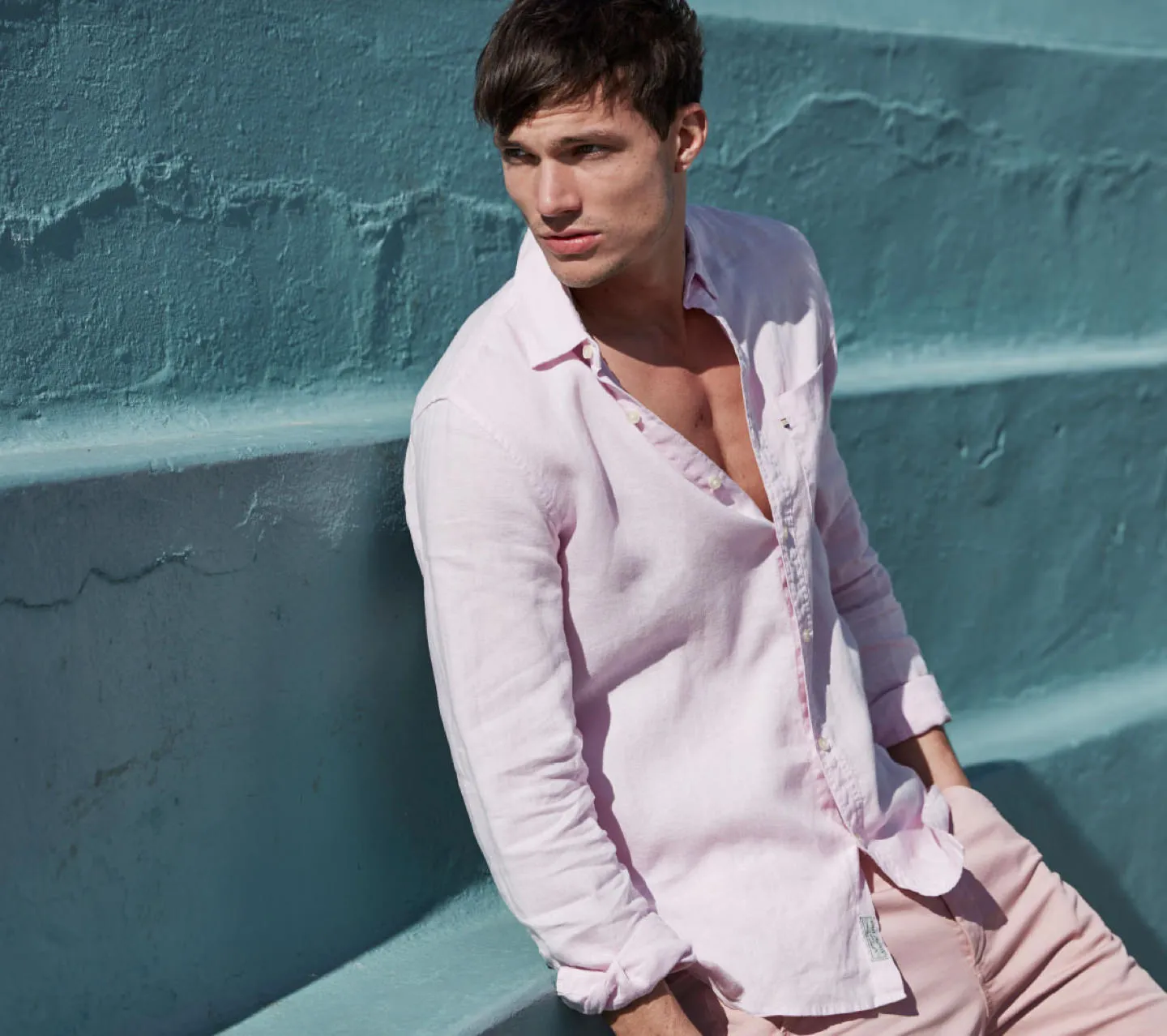 A young man posing in a pale pink suit