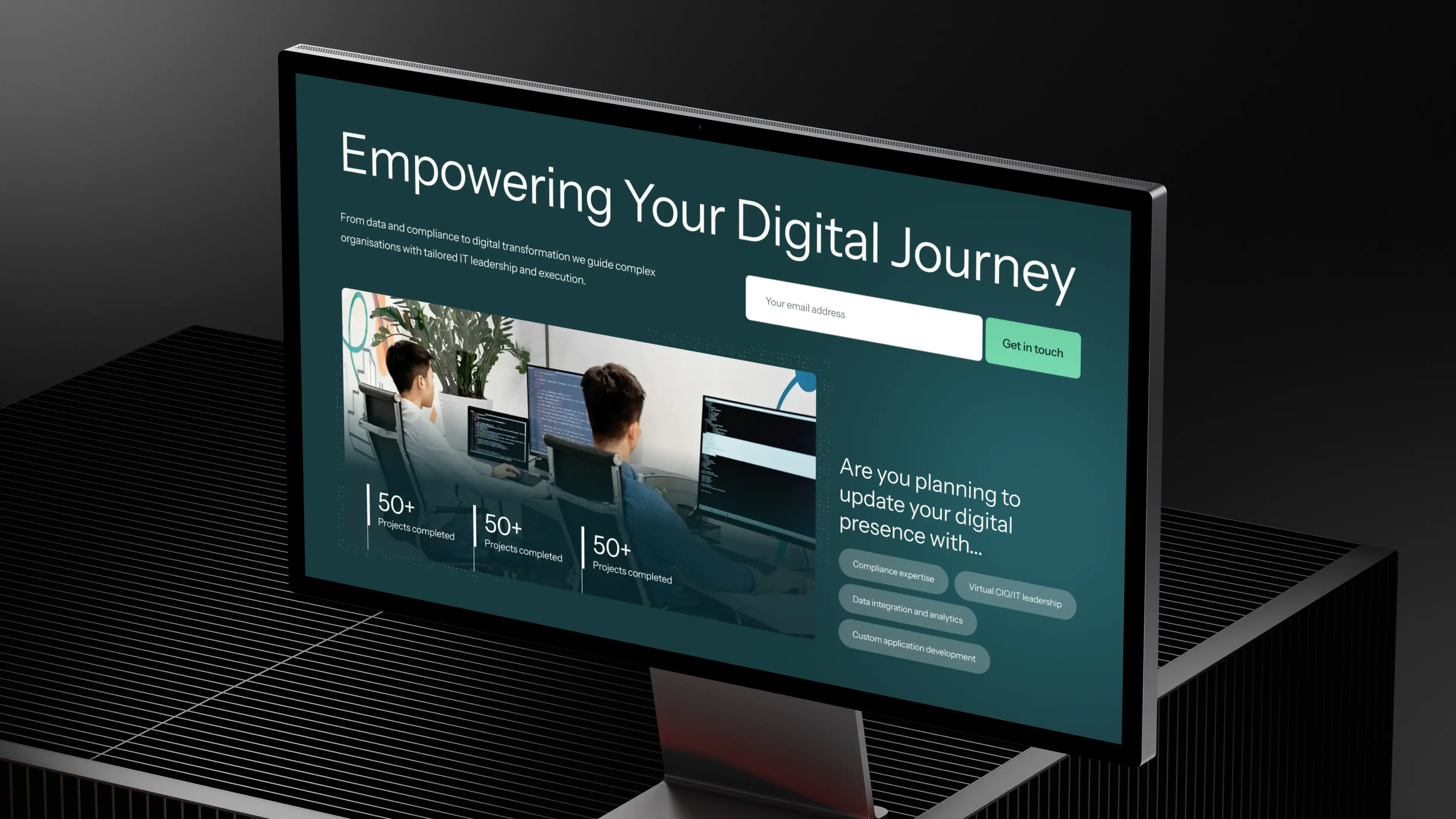 Computer monitor displaying a digital transformation webpage titled 'Empowering Your Digital Journey' with an email signup and service options.
