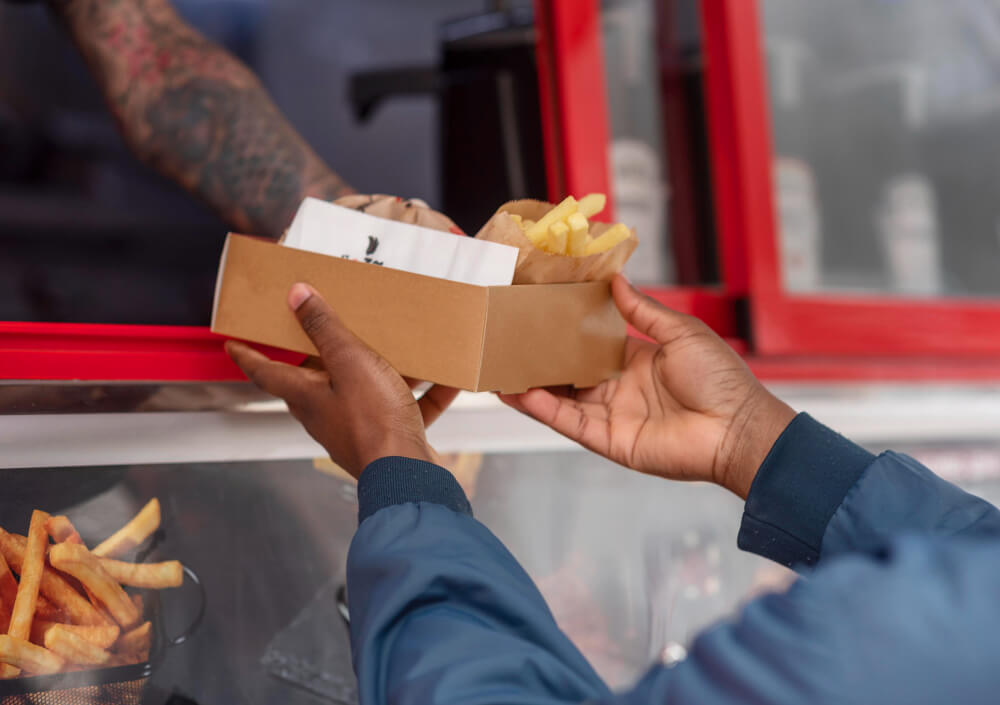 Person taking a take out food from a vendor in a take out truck.