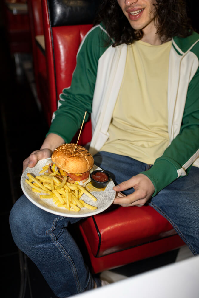Person with a place of burger and fries on their lap.