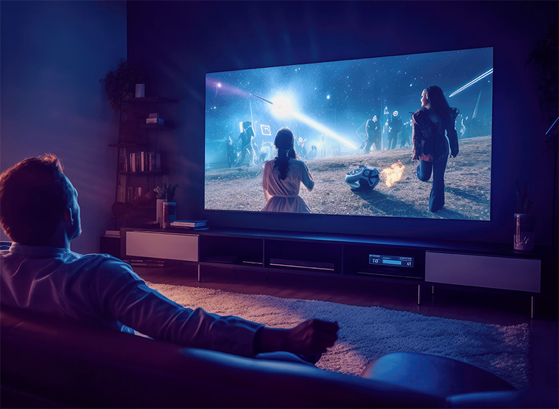 Person watching streaming content on large TV screen in dark living room with blue ambient lighting