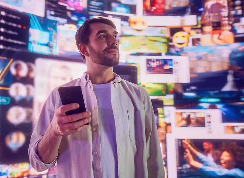 Person with smartphone surrounded by multiple screens displaying apps, representing digital ecosystem