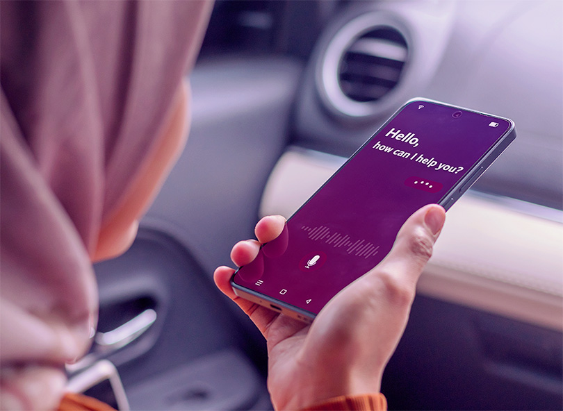 A woman in a car holding a smartphone to use virtual voice assistant