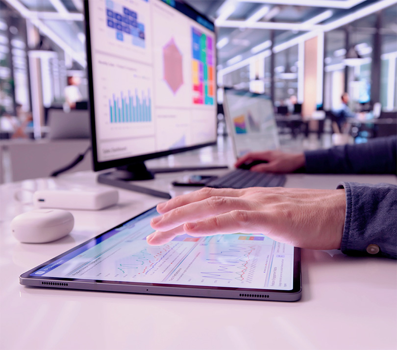 A marketer reviews campaign performance data across a tablet and monitor in a modern analytics workspace, highlighting the complexity of measuring ad effectiveness.