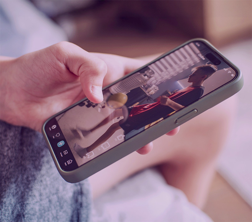 Close-up of a hand holding a smartphone playing a short-form vertical video on a social media app.
