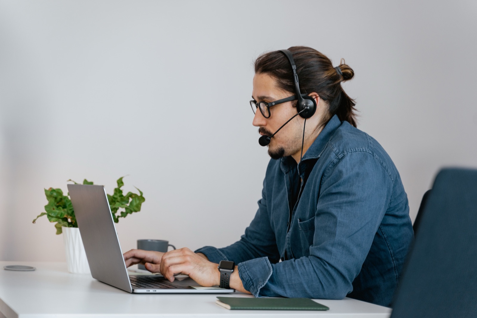 Person mit Headset arbeitet konzentriert am Laptop