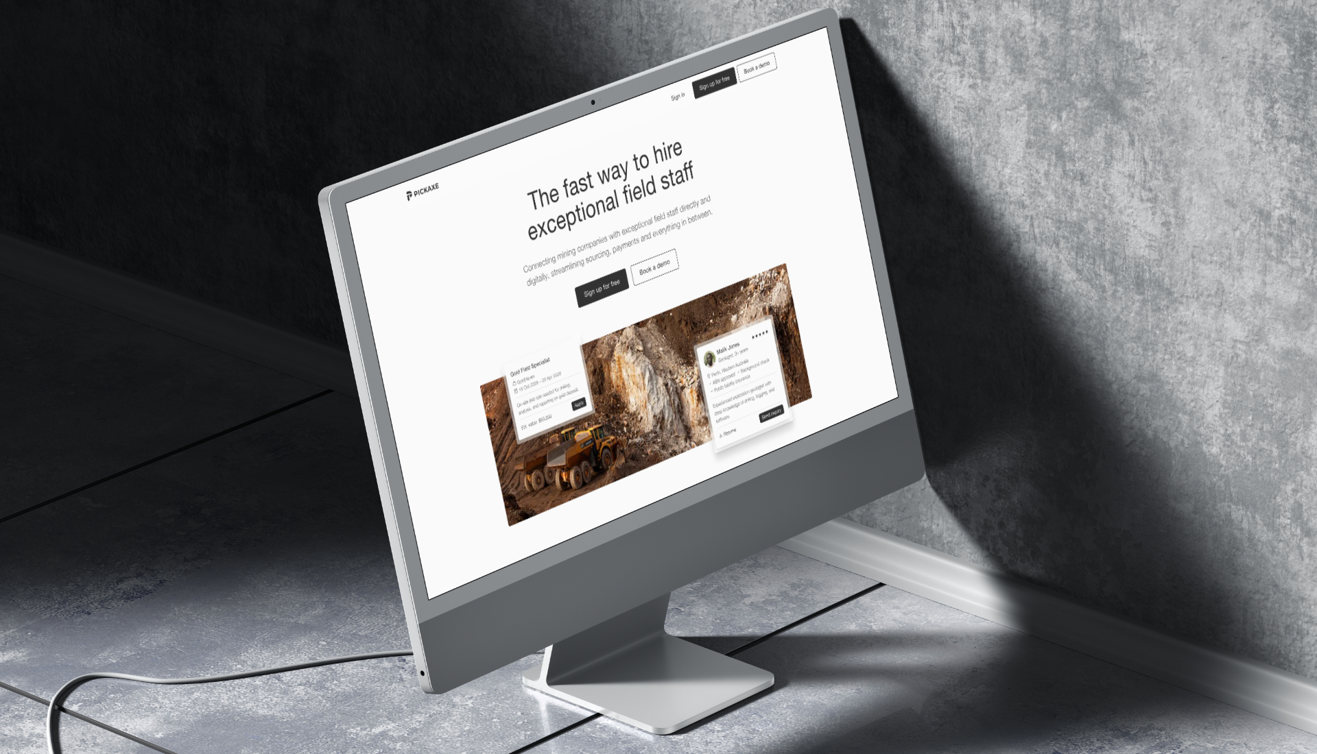 Desktop monitor on a floor showing a website for hiring exceptional field staff in mining with job listings and a mining truck image.