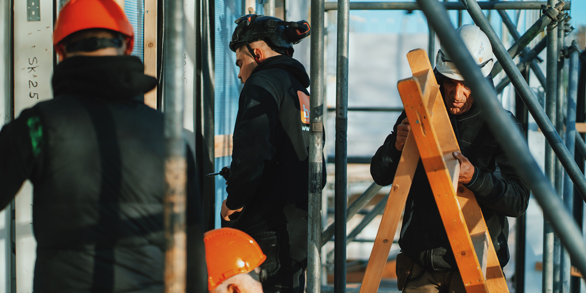 BNU-vakmannen aan het werk op een bouwplaats met steigers