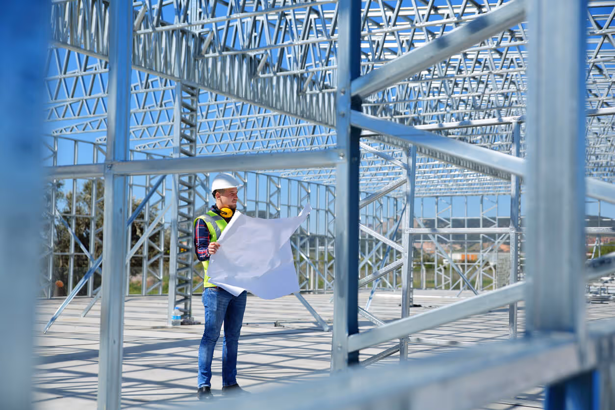 worker in the middle of a construction site with a blueprint in his hand