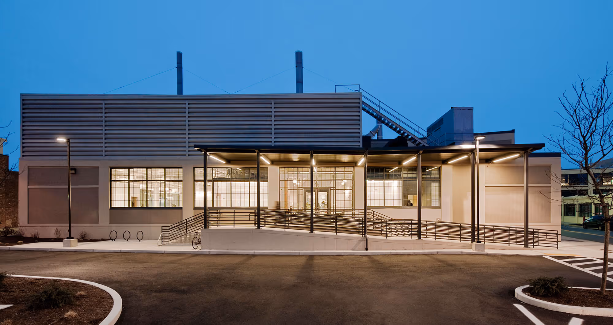Modern industrial building with glass windows and accessible ramp at dusk