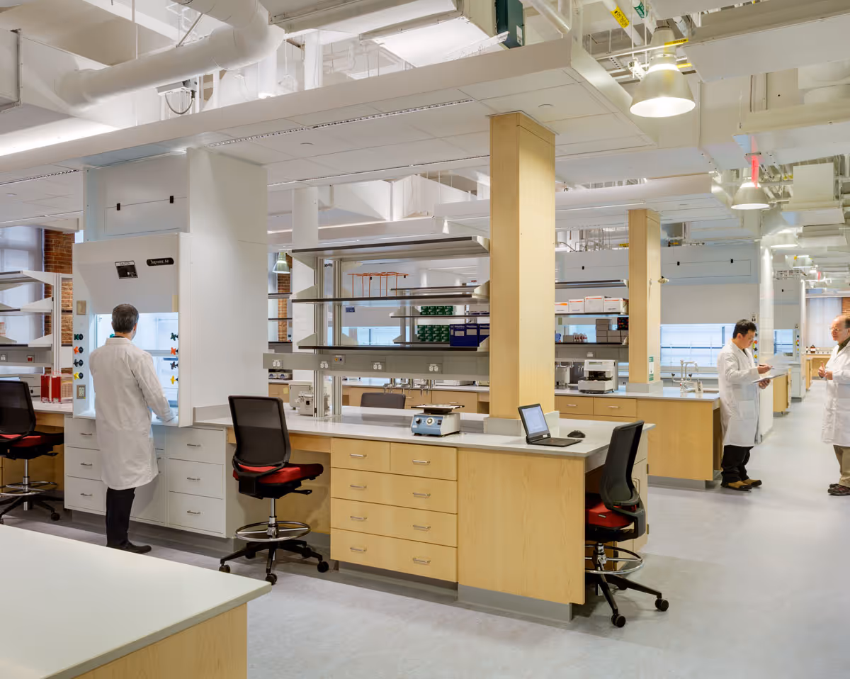 Three scientists in a spacious, modern lab with workstations, lab equipment, and whiteboard.