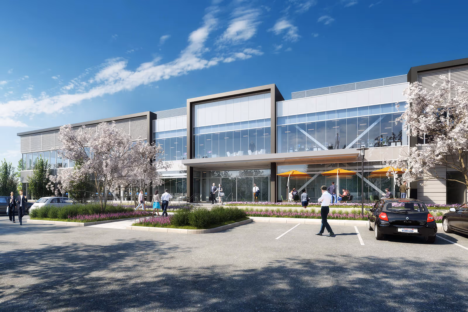 Modern glass office building with flowering trees and landscaped parking area