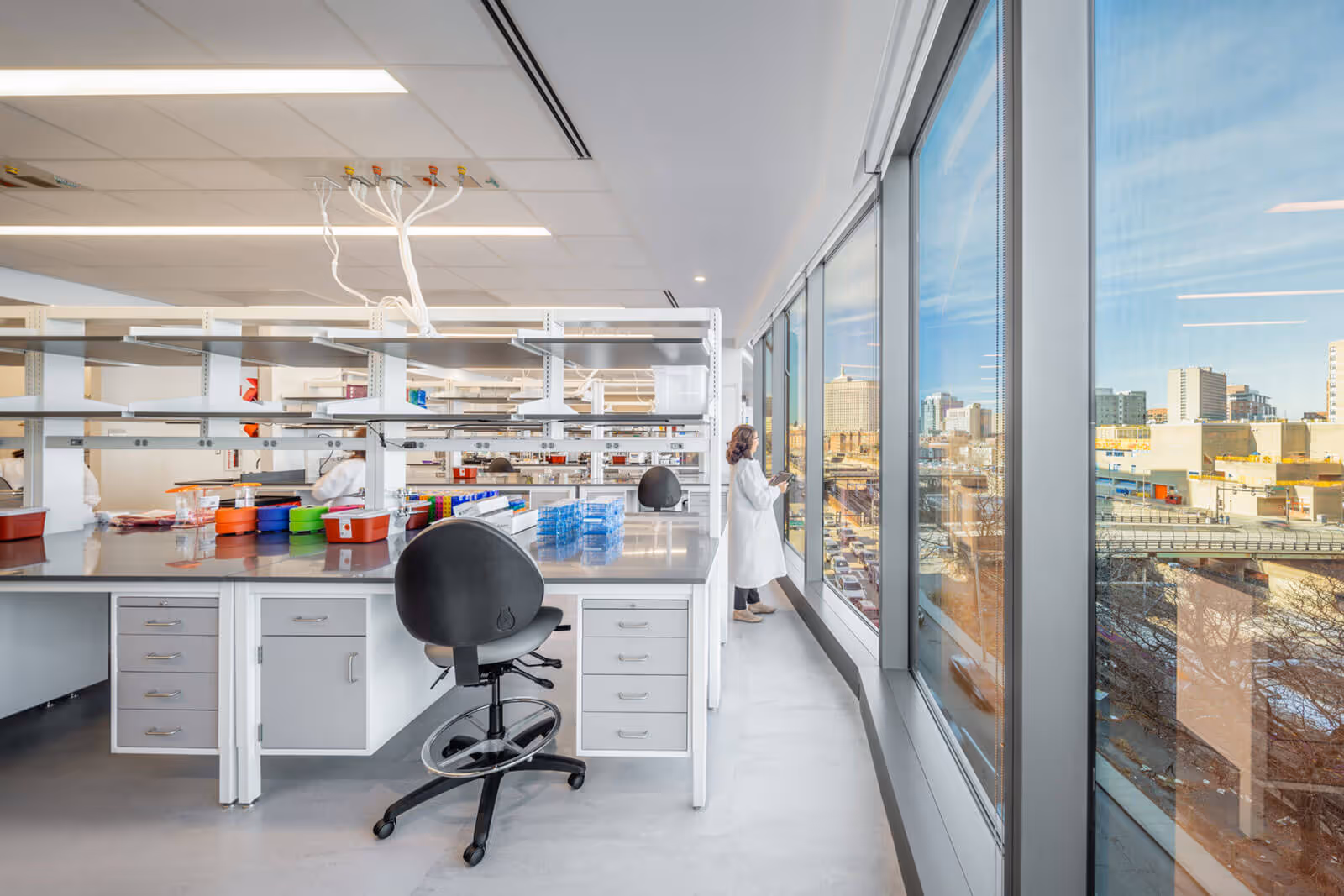 Modern laboratory with white shelves, colorful containers, and city view