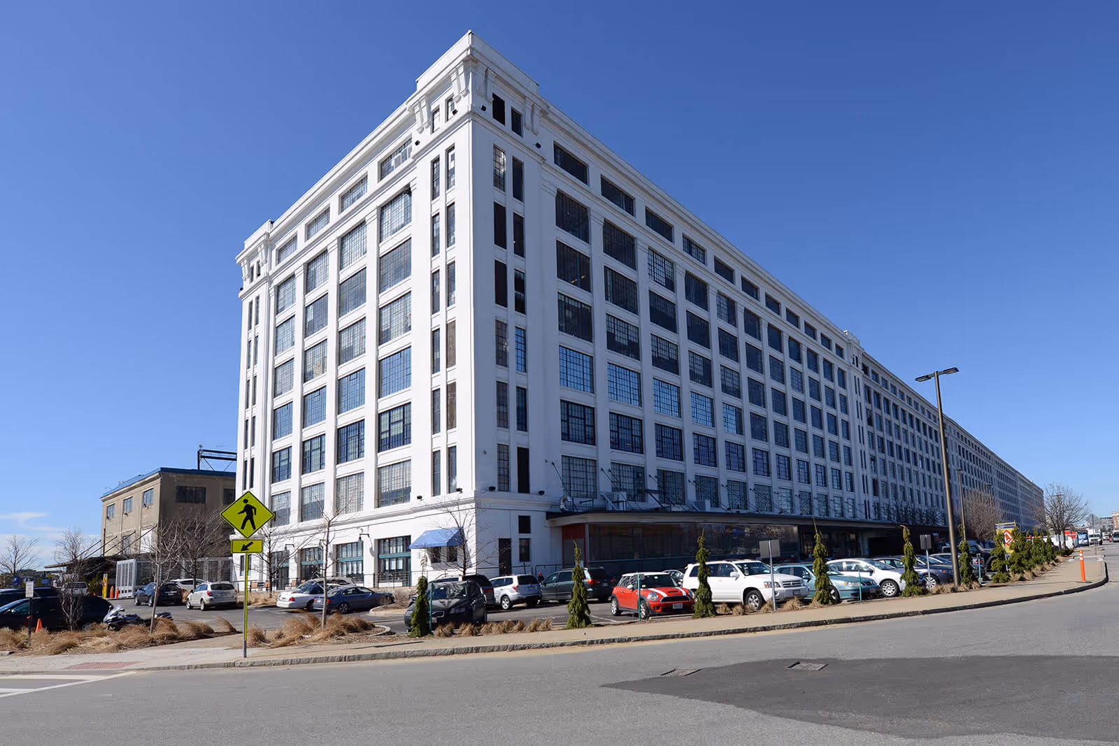 Large white multi-story office building with many windows and parking lot
