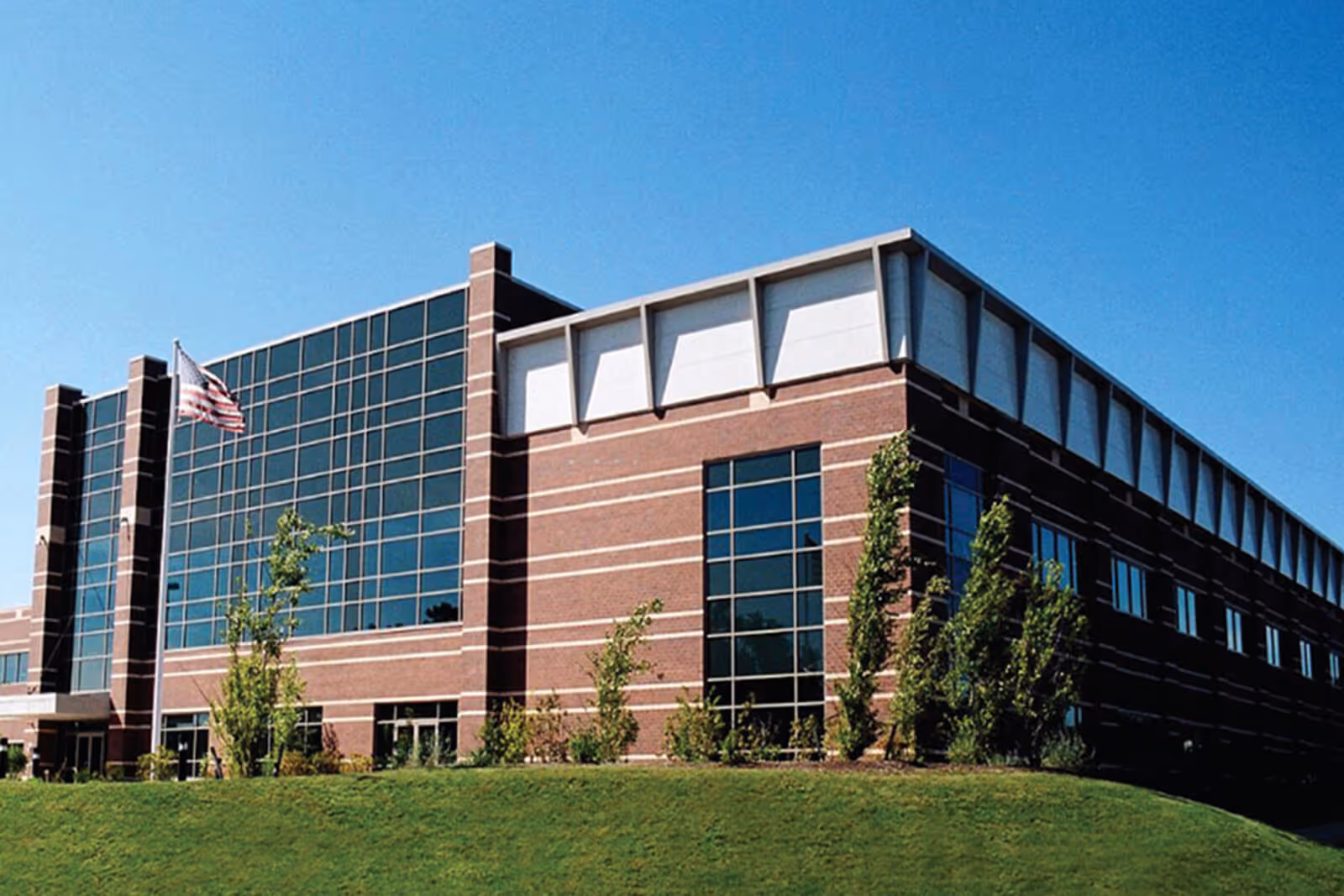 Modern brick and glass office building with American flag on sunny day