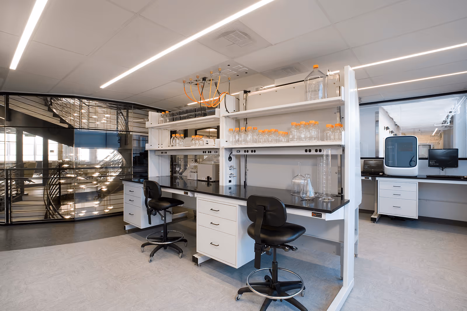 Modern scientific laboratory with white shelves, glass bottles, and workstations