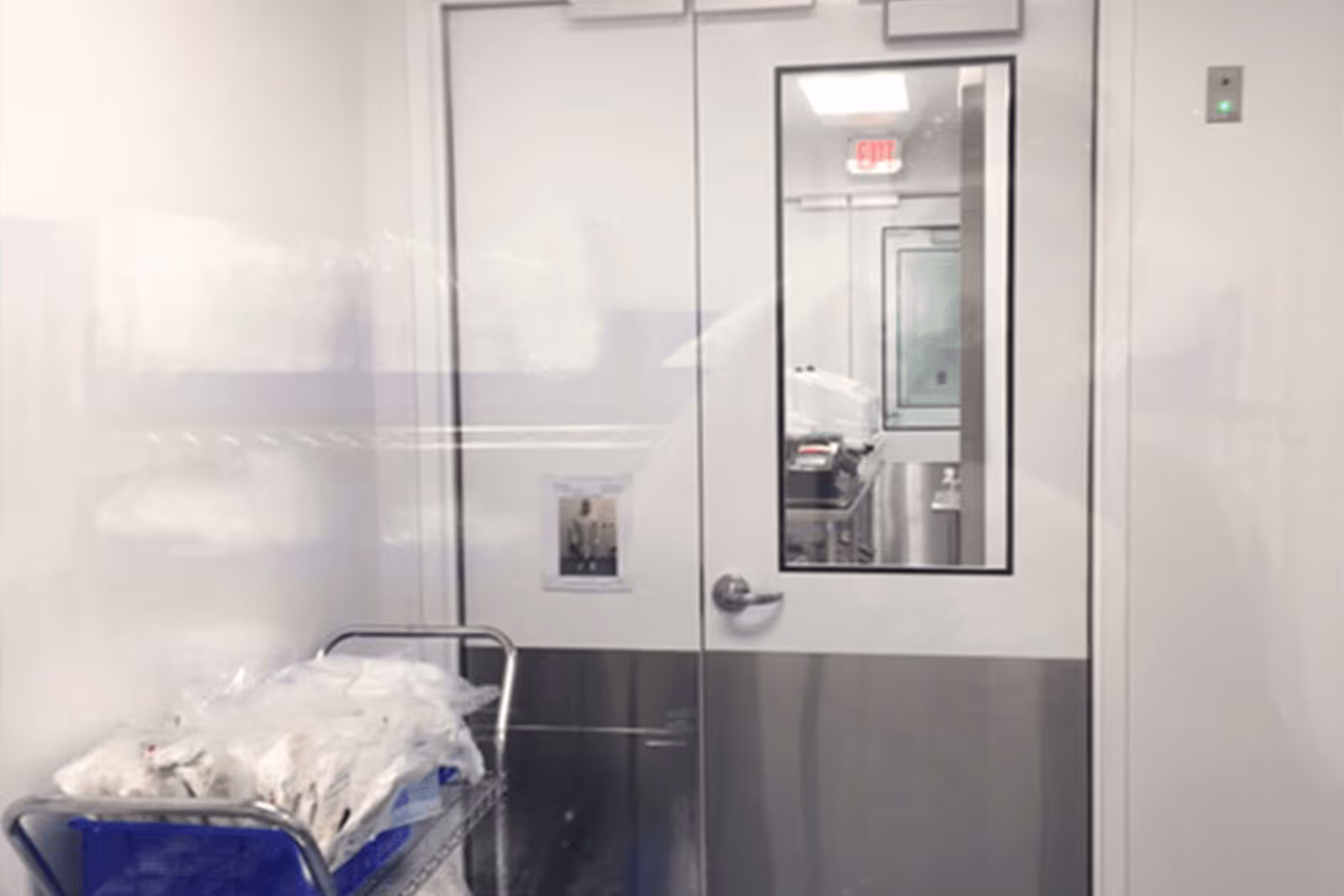 Clean medical or laboratory room with metal door and industrial cart