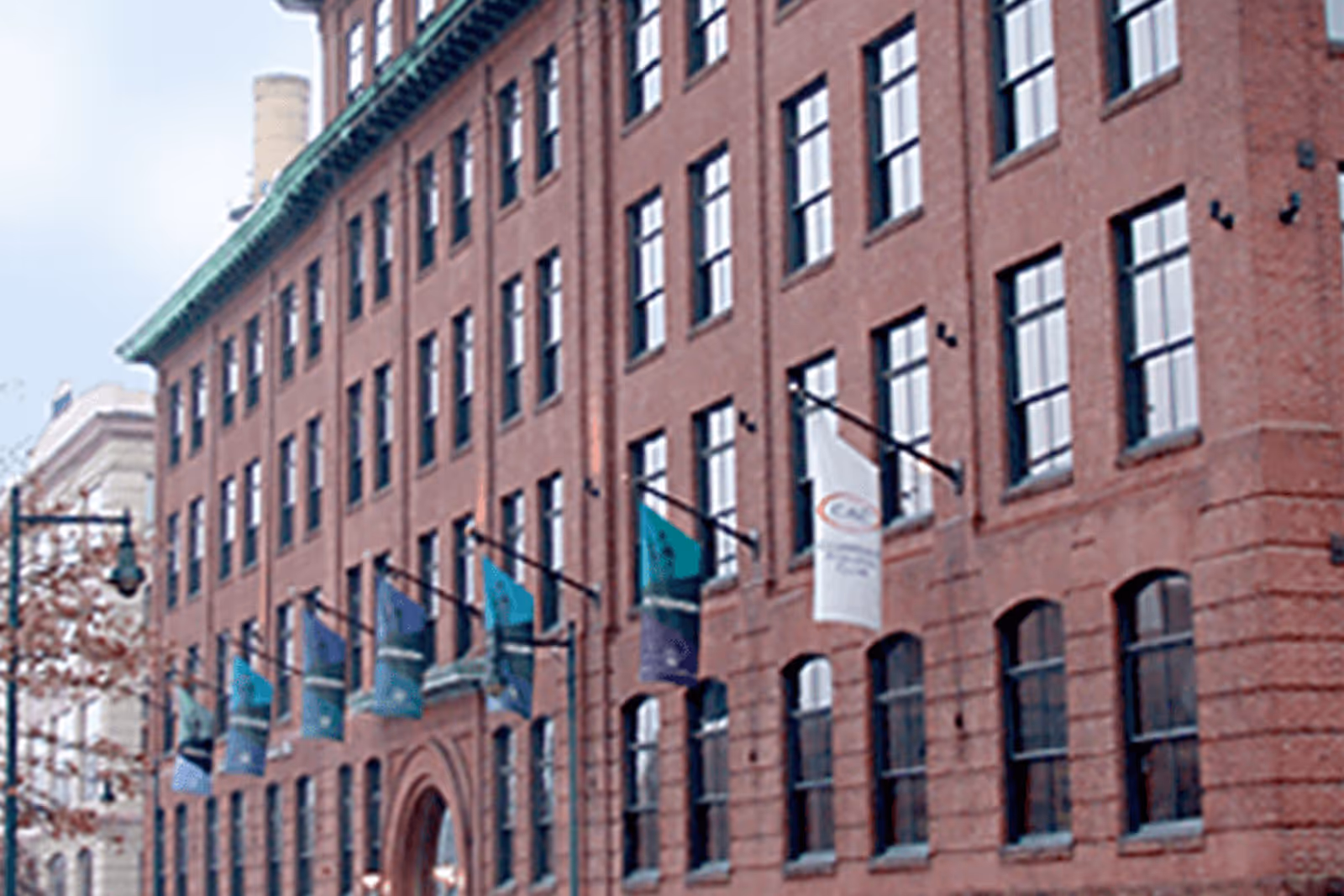 Red brick building with multiple windows and hanging blue-green flags