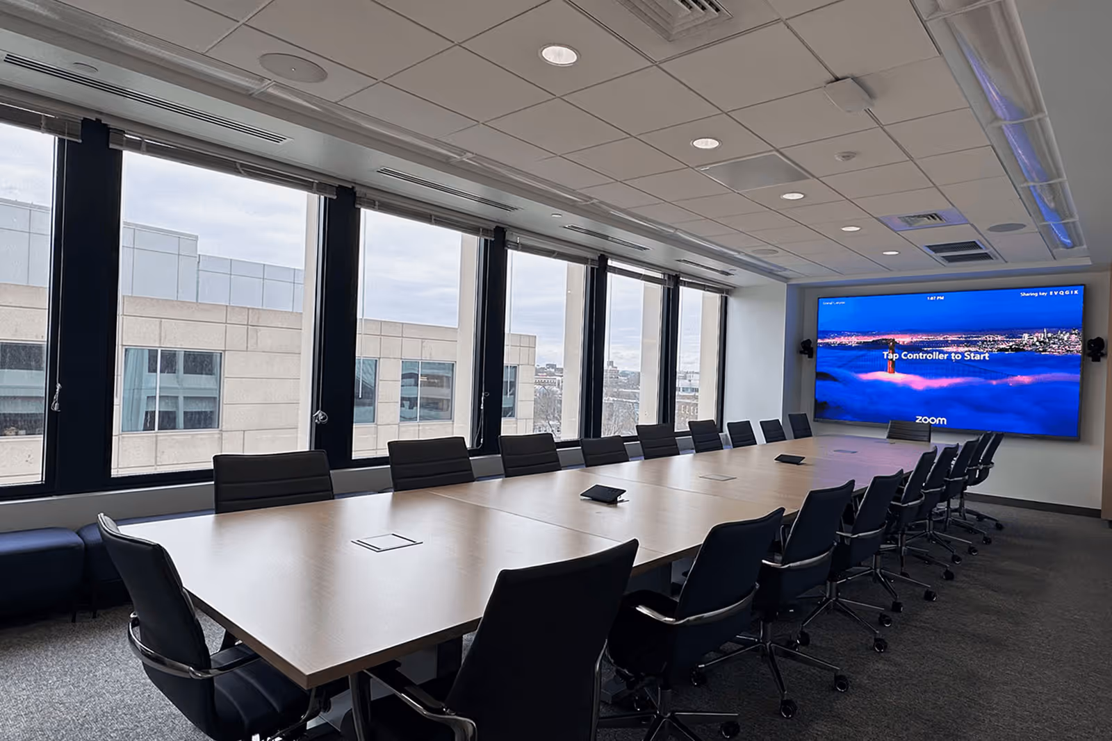 Modern conference room with large windows, long table, and Zoom screen