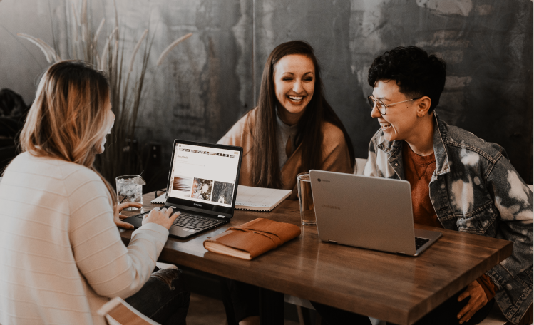 Three colleagues working at a desk together while having a conversations