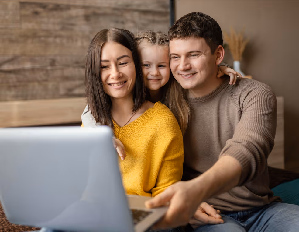 Family smiles as they look at computer