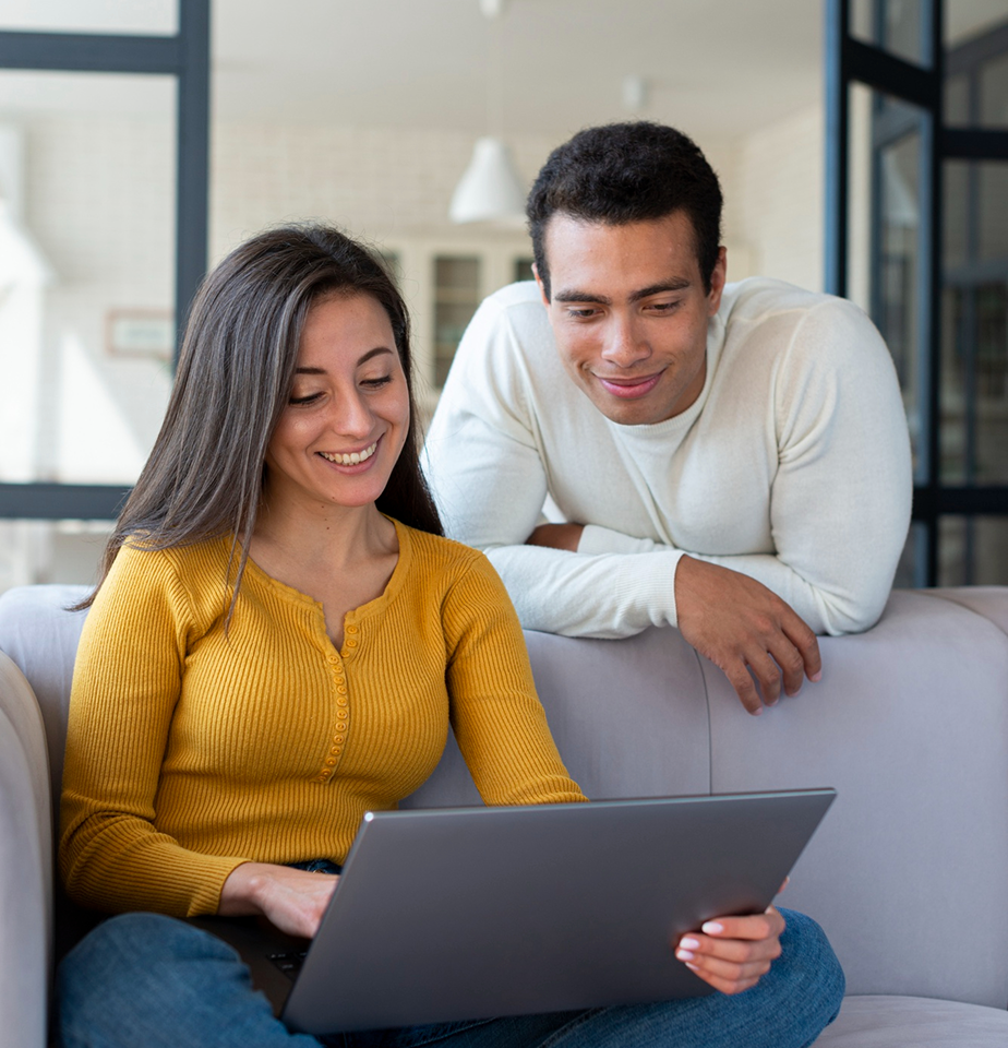 Man and woman look over a computer screen and smile