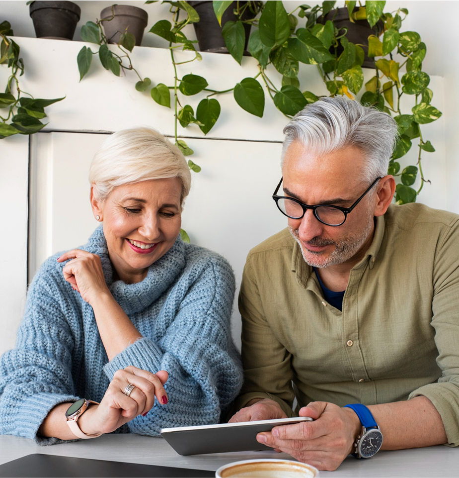 Man and woman look over tablet device while smiling