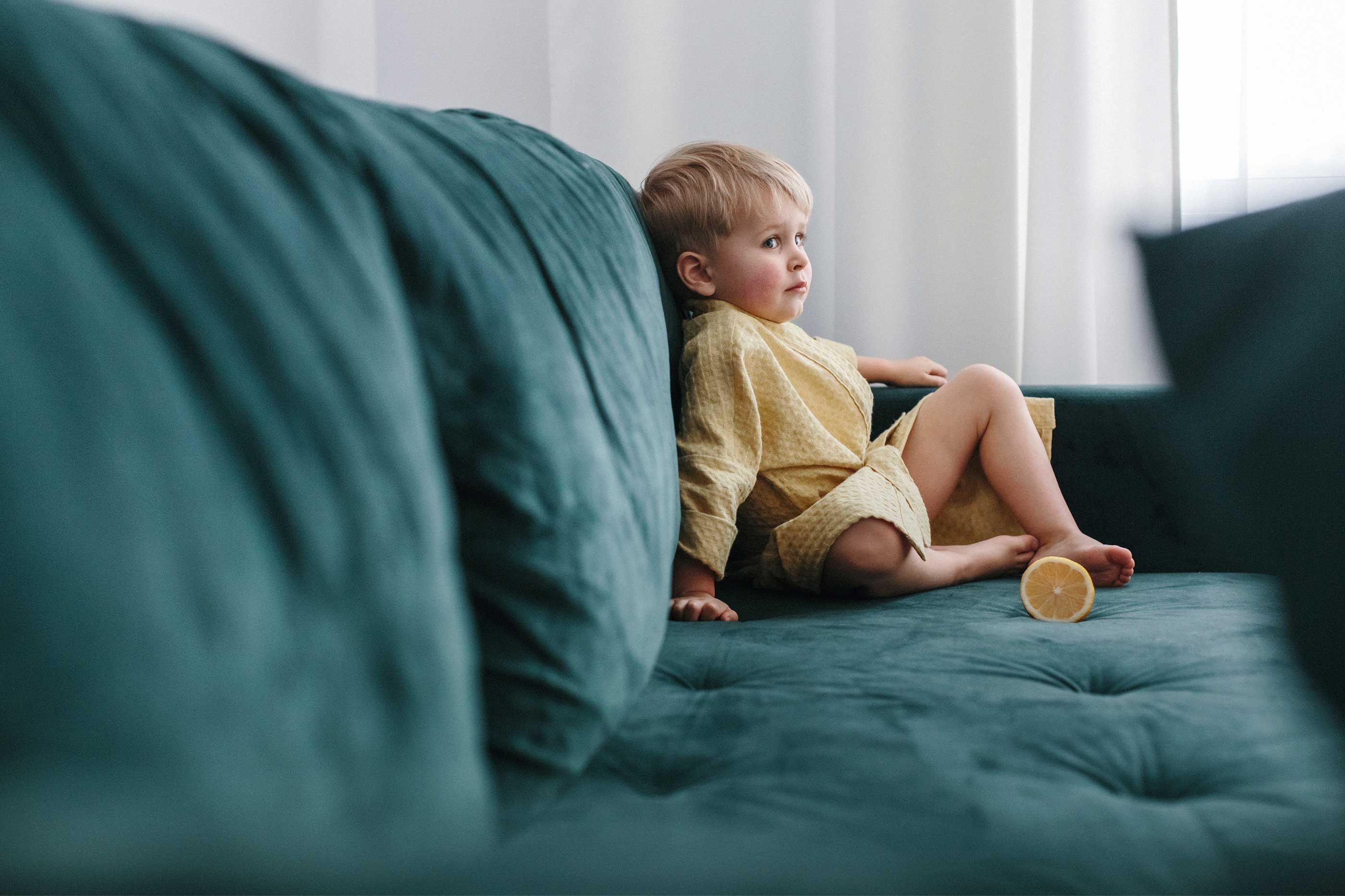 2 year old boy sitting in green coach