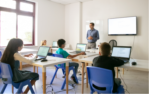 Teacher leading a computer class with students on laptops
