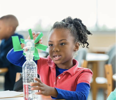 Student building a windmill model with a plastic bottle in class