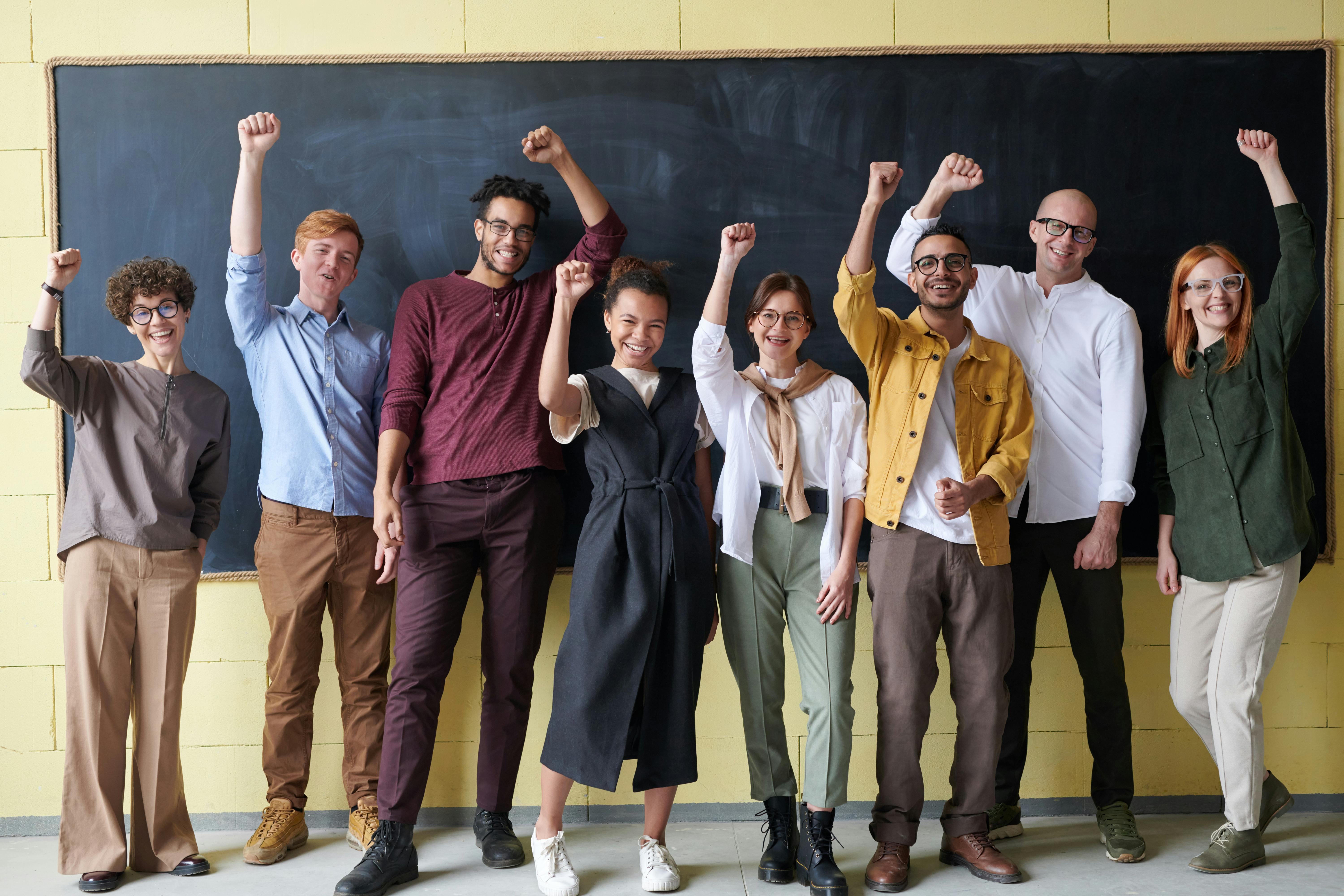 Diverse school staff celebrating together in front of a chalkboard
