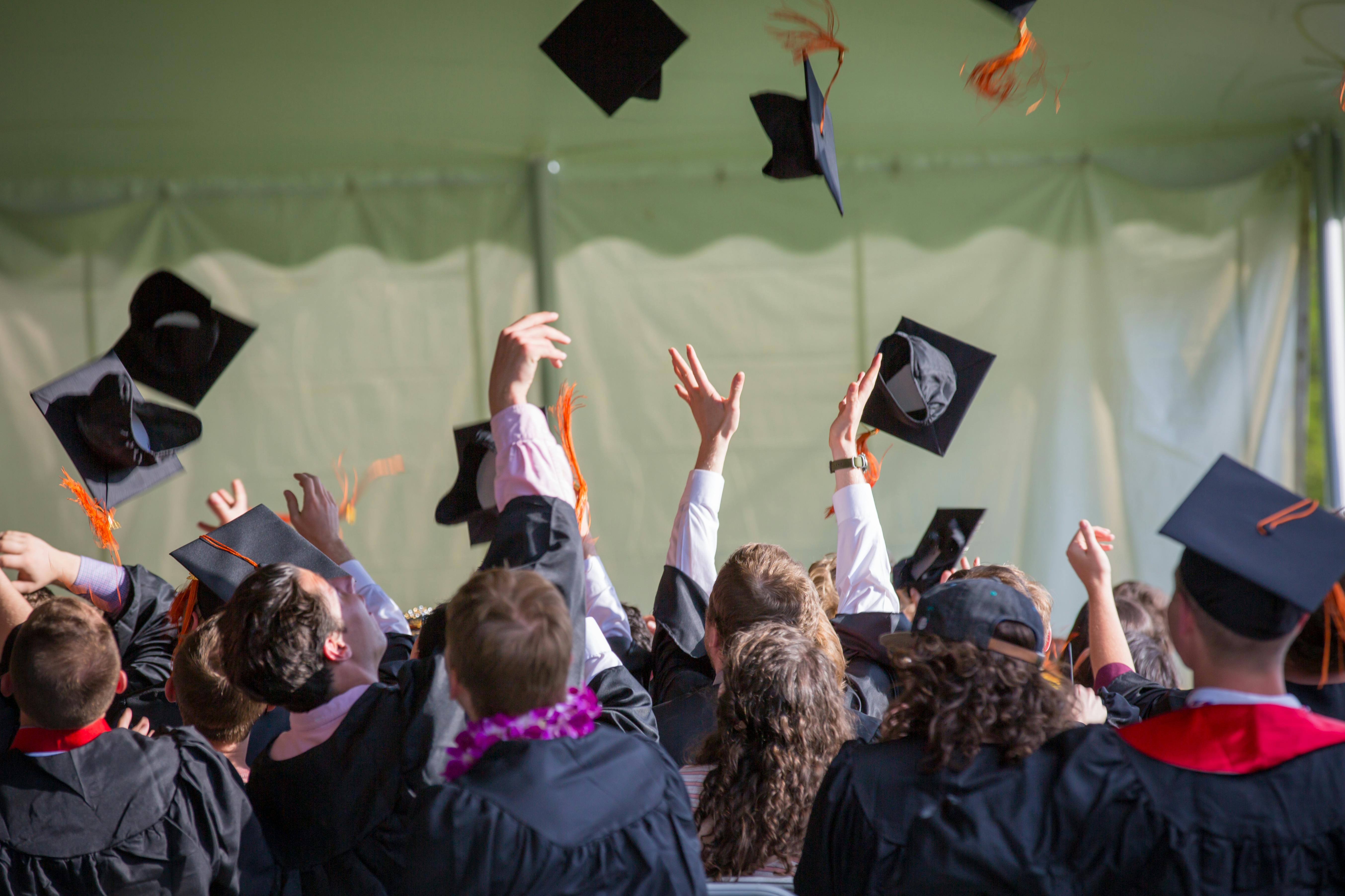 Graduates in black robes tossing caps into the air