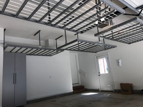 Gray car parked in a clean garage with white cabinets, drawers, and organized shelves along the back wall for optimal garage storage.