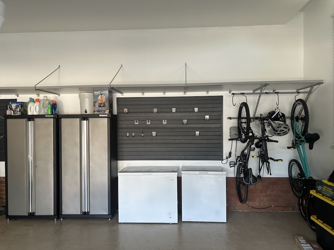 Gray car parked in a clean garage with white cabinets, drawers, and organized shelves along the back wall for optimal garage storage.