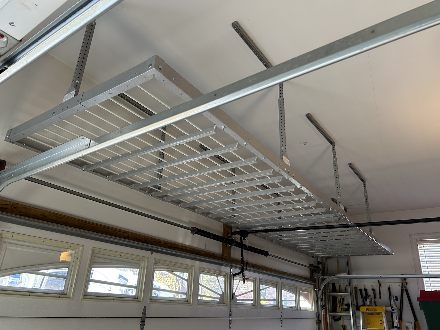 Gray car parked in a clean garage with white cabinets, drawers, and organized shelves along the back wall for optimal garage storage.