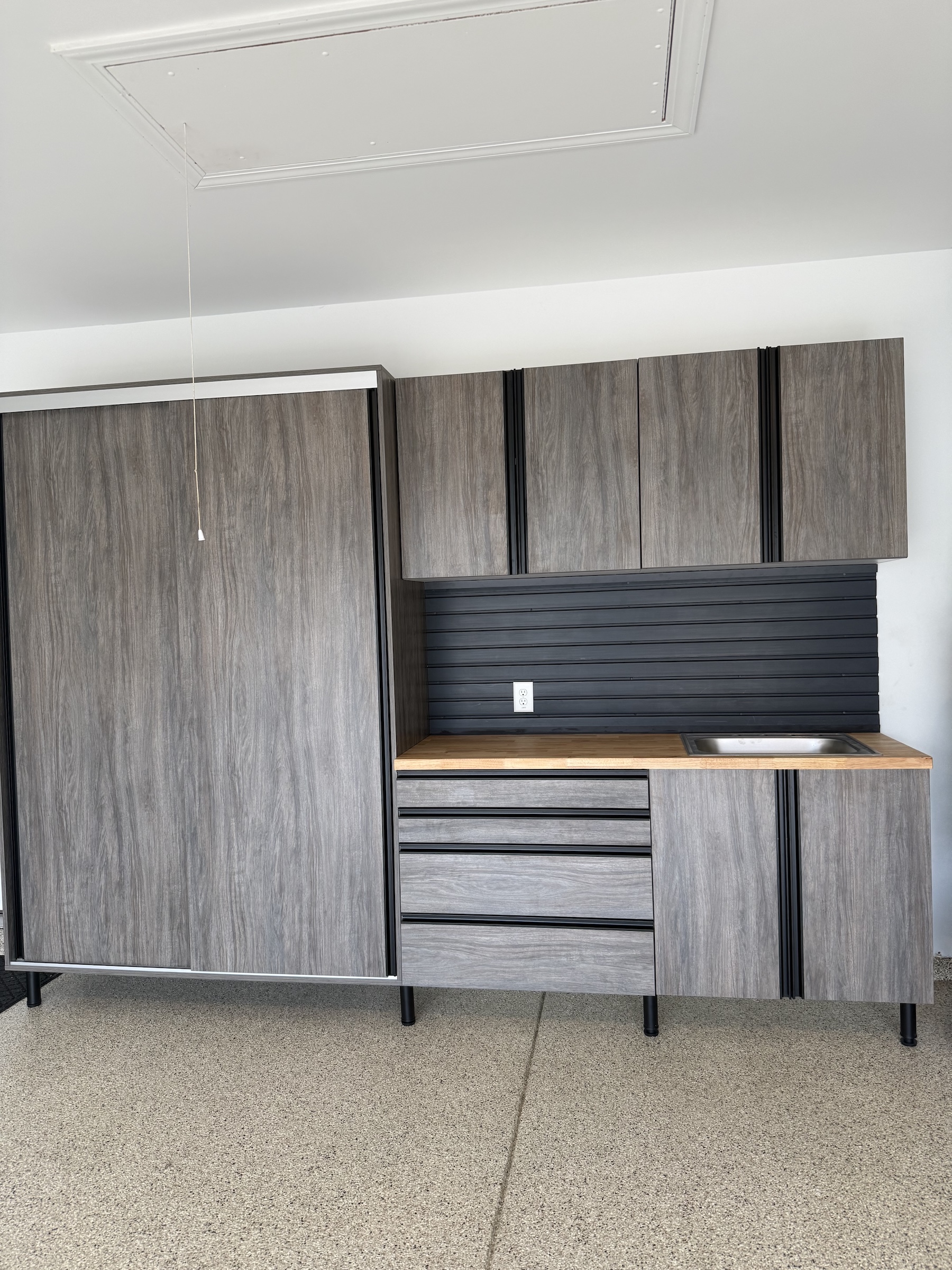 Gray car parked in a clean garage with white cabinets, drawers, and organized shelves along the back wall for optimal garage storage.