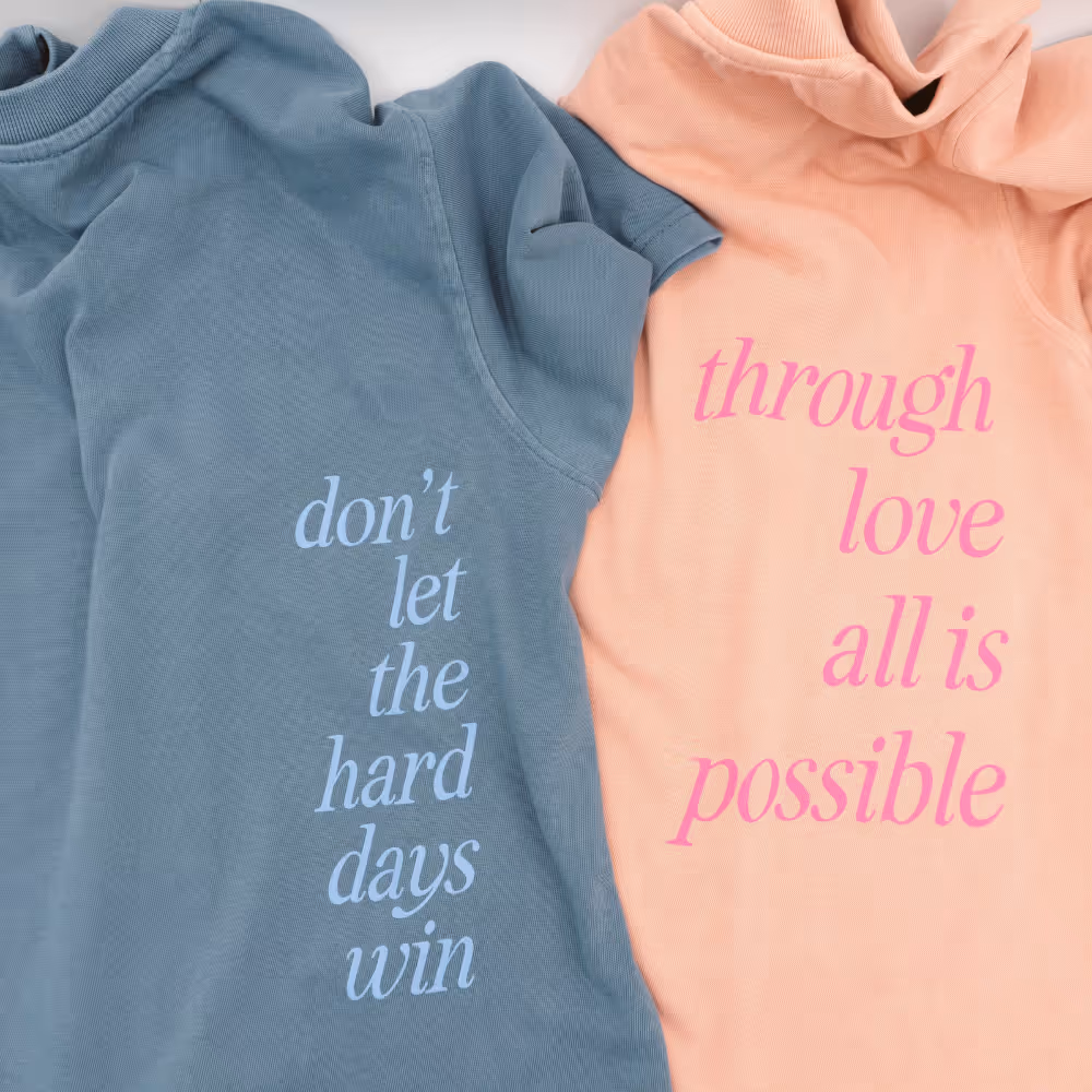 Pastel blue and peach shirts with motivational quotes printed in script fonts.