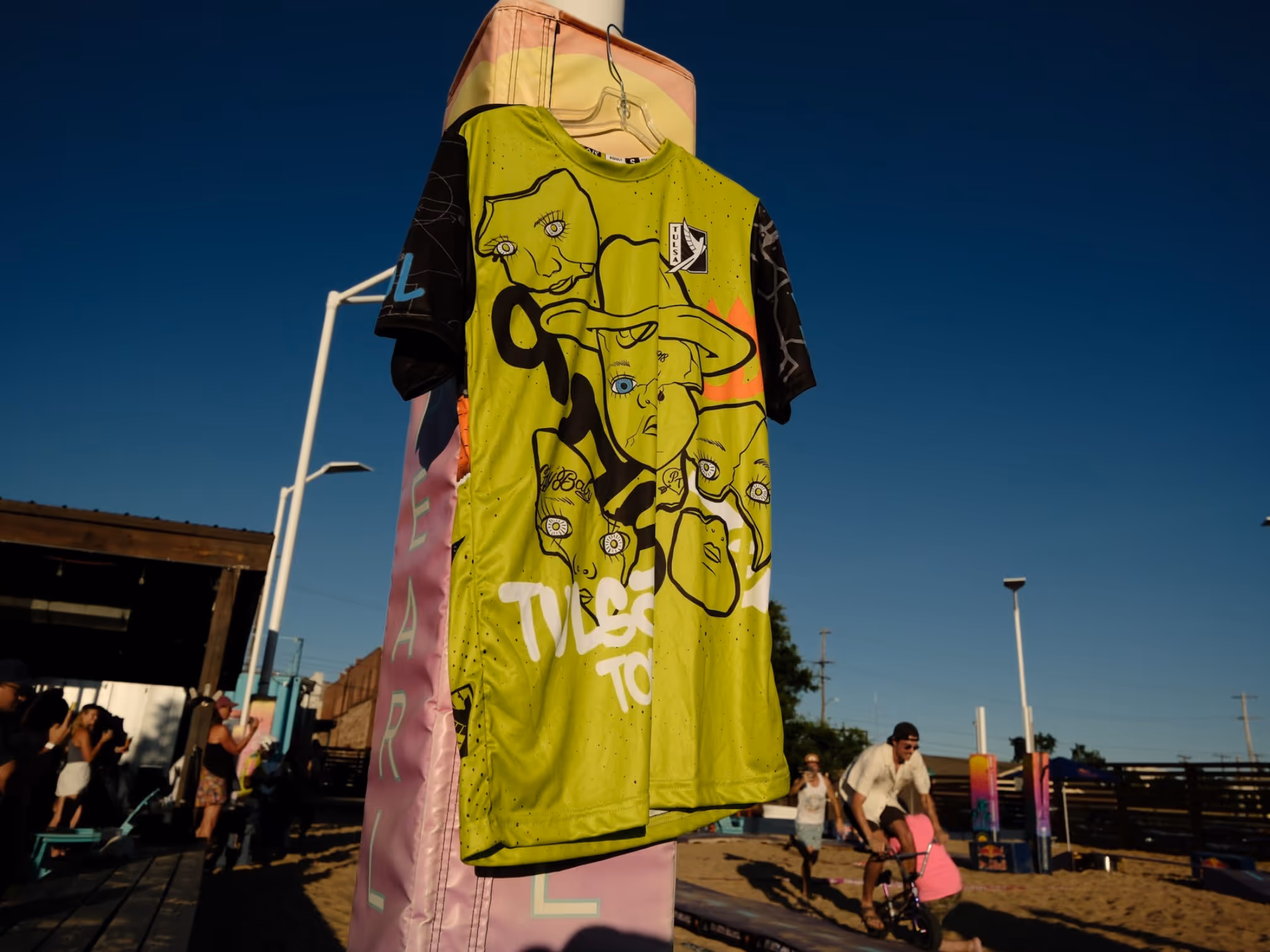 Custom soccer jersey with bold abstract face art and “Tulsa Tough” lettering displayed outdoors at sunset.