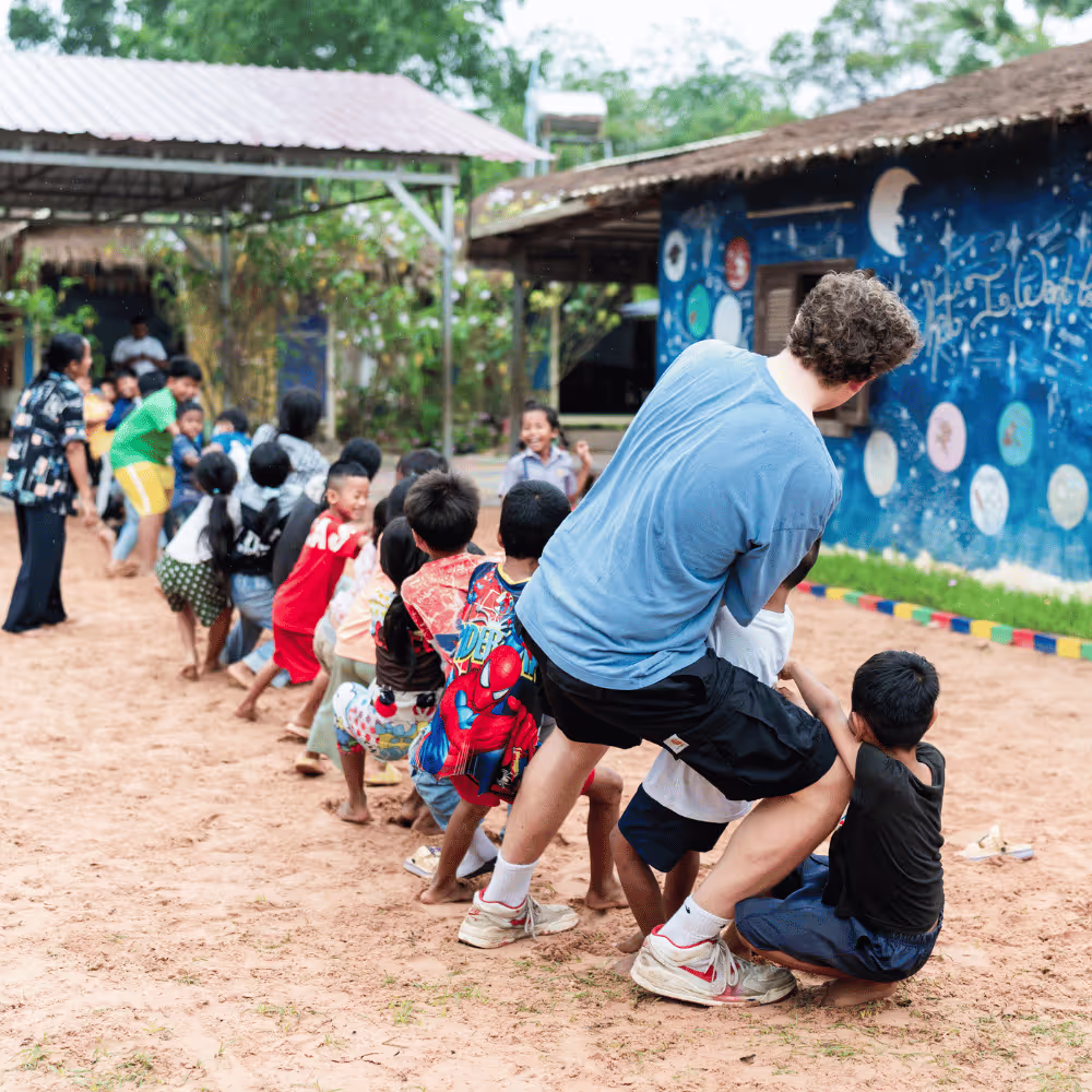 Cambodian school kids playing tug of war with a Leaper on a Gap Year adventure with The Leap