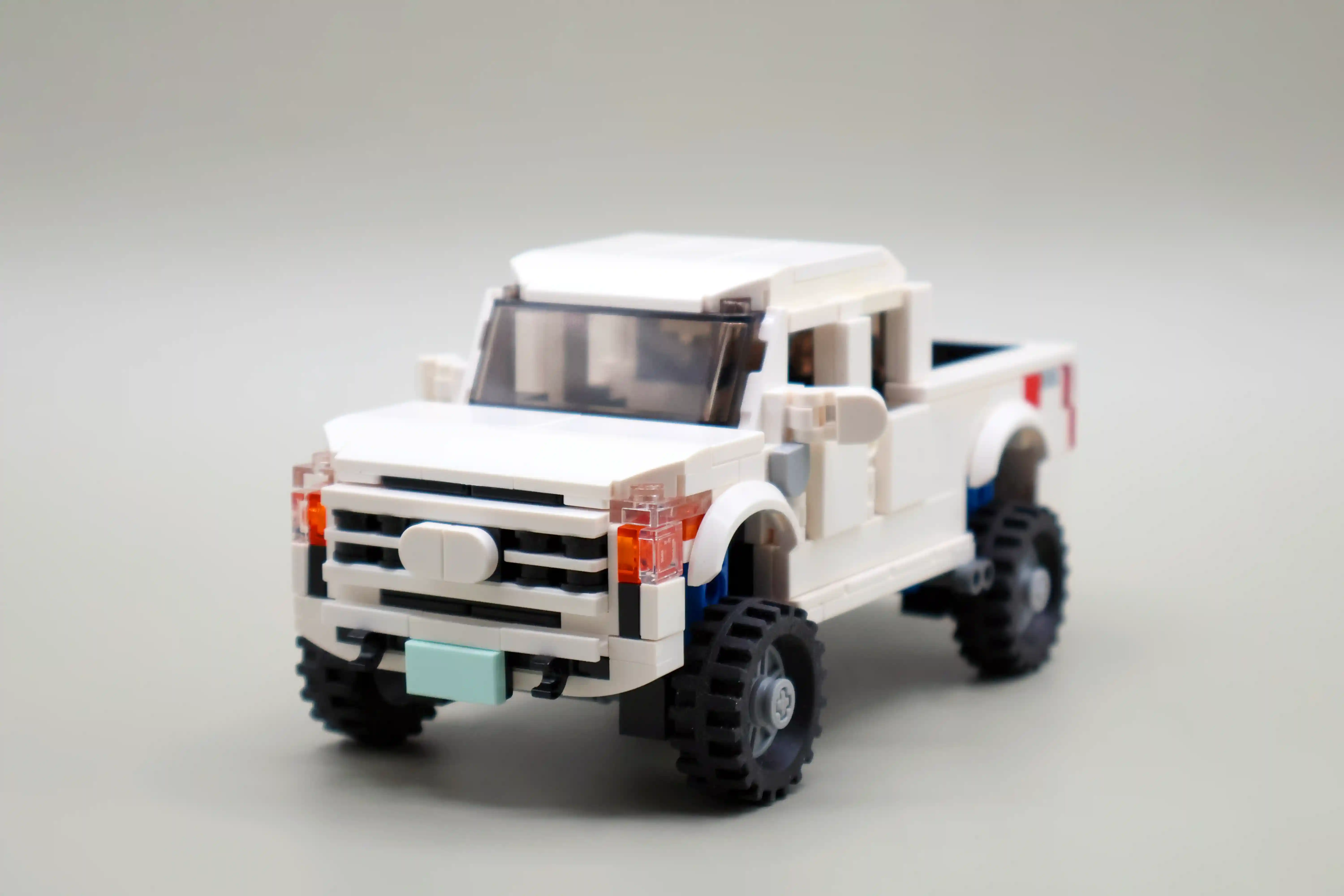 A custom LEGO commission by Ben Brickson of a white Ford F250 Truck with lift kit.