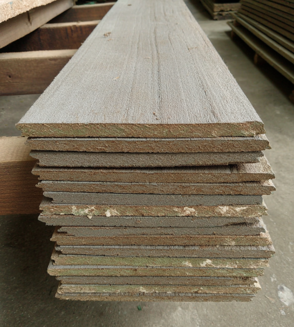 Close-up stack of unfinished wooden siding planks showing the cut edges.