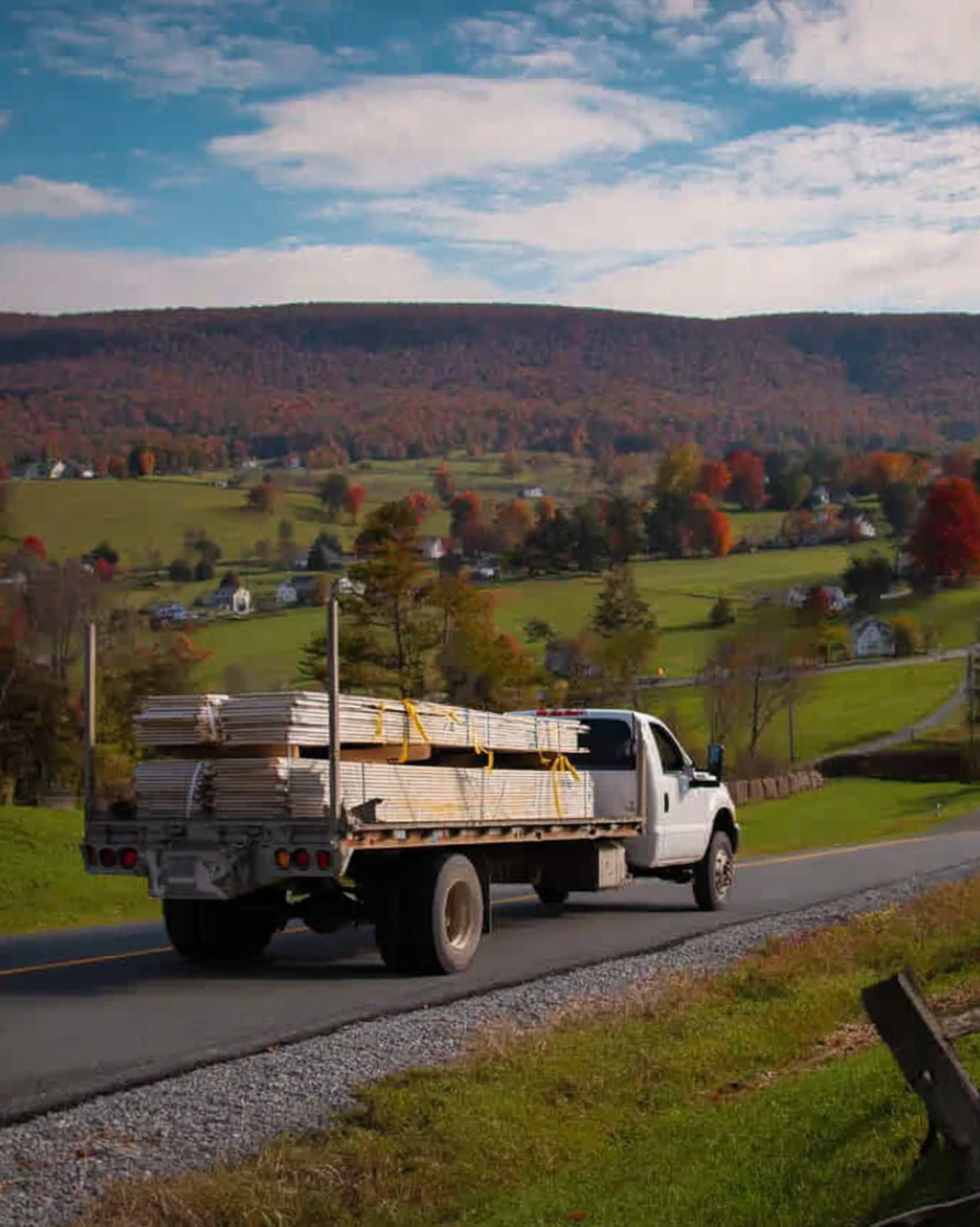 Flatbed truck transporting lumber through countryside road – timber delivery service