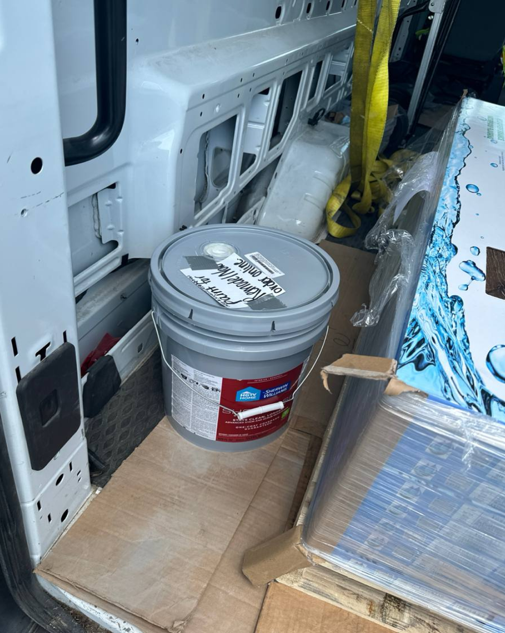 Gray paint bucket labeled "exterior clear sealer" inside delivery van.