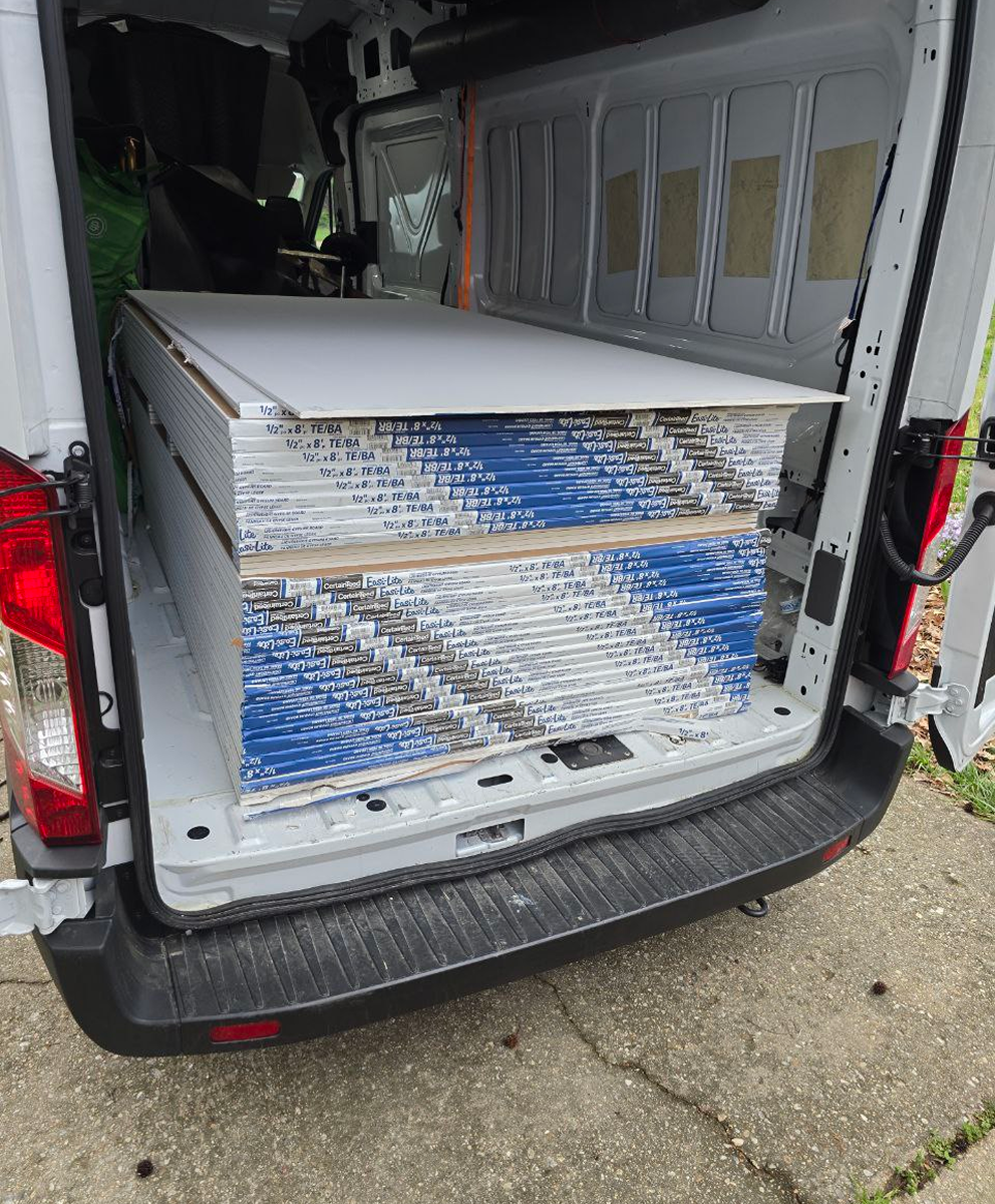 Van packed with stacked drywall sheets and sheetrock for building project supply.