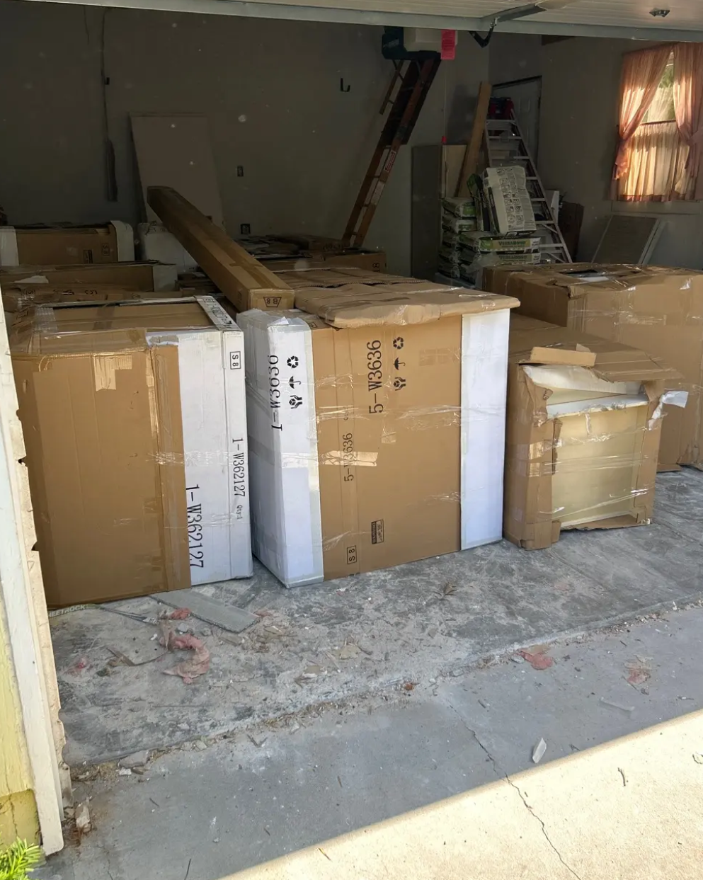 Bathroom vanities in cardboard packaging stored inside a garage during renovation.