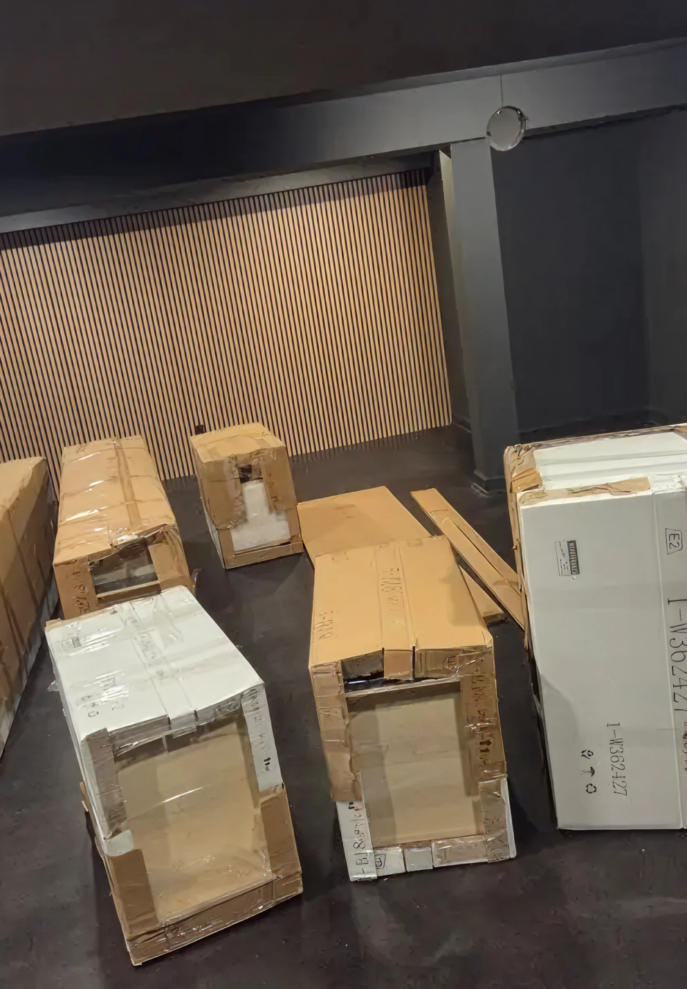 Multiple bathroom vanity cabinets in shipping boxes stacked inside a dark storage room.