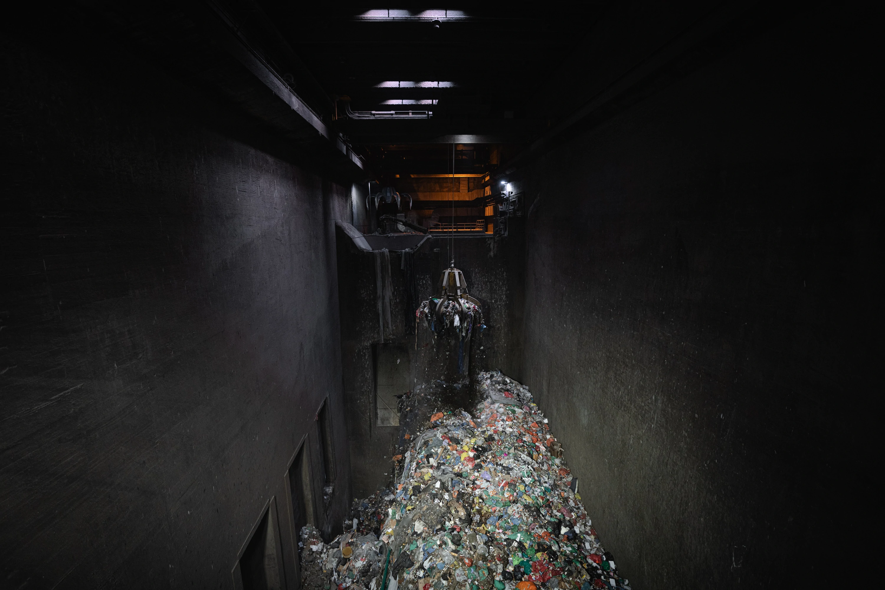 A crane grab lifting waste inside the bunker of a waste-to-energy plant