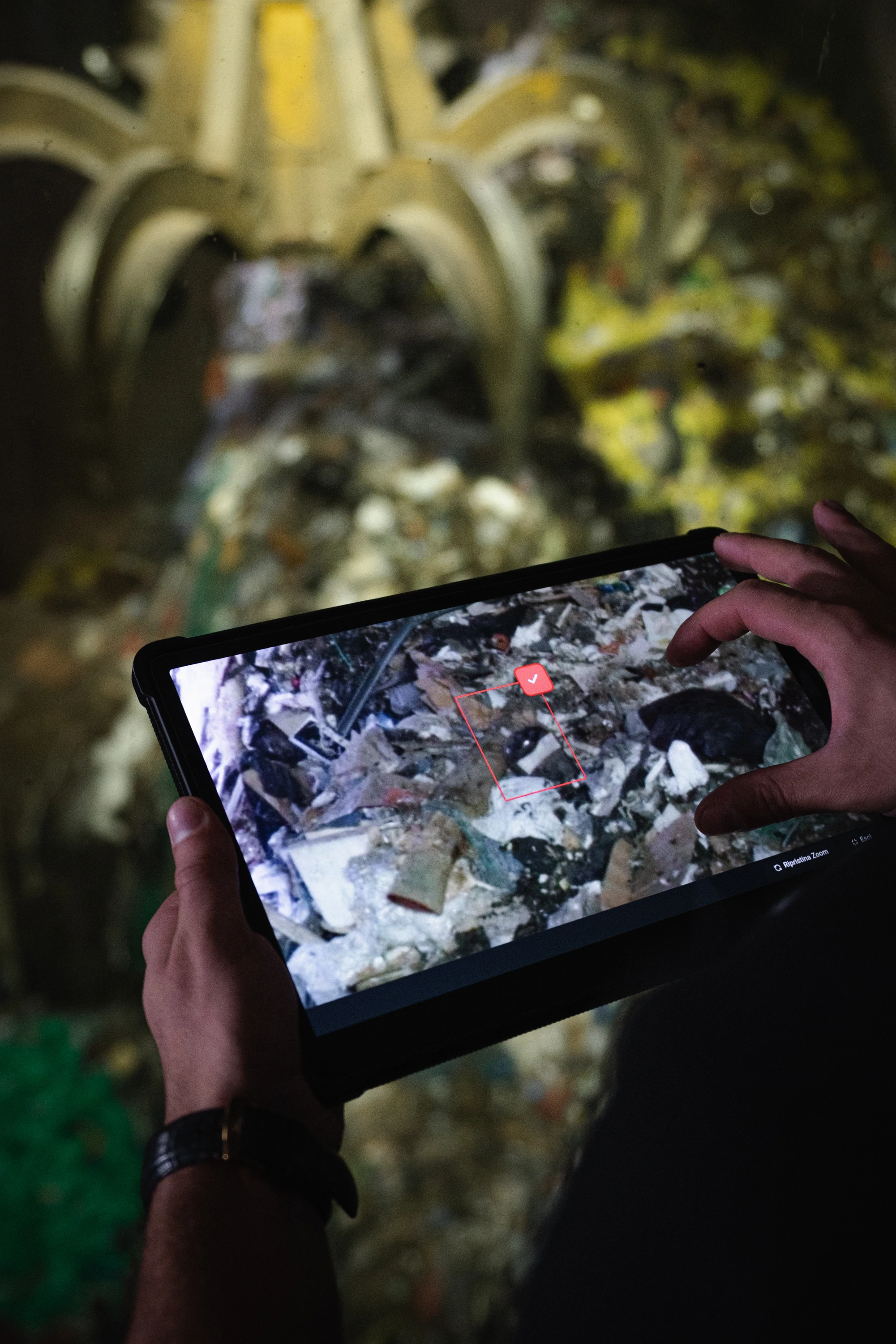 A plant operator holding a tablet that shows Jaipur’s system flagging a hazardous item in the waste pile